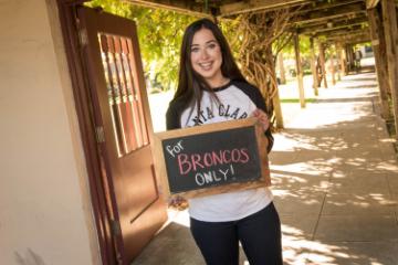 A student holding a slate which has the text